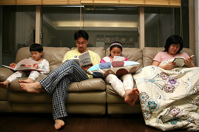 다같이 쇼파 위에서 책을 읽고 있는 가족의 모습이다.