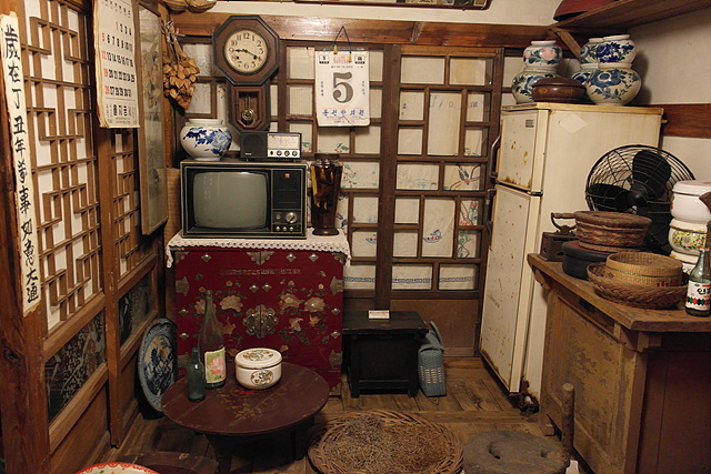한국 근현대사 박물관 내부 모습으로 창호지를 바른 미닫이 문과 벽시계 숫자가 큰 달력 구형 TV와 냉장고 등이 있는 옛날 방 모습
