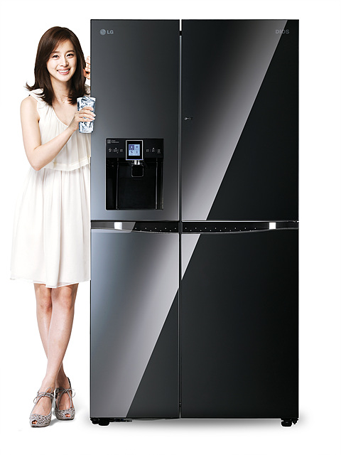 블랙 색상의 정수기 냉장고 앞에 하얀 원피스를 입은 김태희가 물 컵을 들고 서 있다.