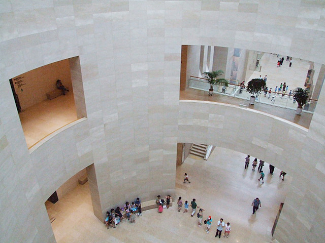 박물관의 내부를 위에서 찍은 사진으로 많은 사람들이 구경하고 있으며 벽 사이사이가 뚫려 있는 모습이다.