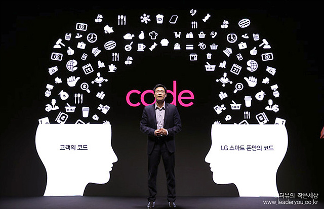 코드를 설명하고 있는 모습이다. 남자가 중앙에 서있고 양 옆으로 고객의 코드와 LG스카트 폰안의 코드라는 글귀가 적혀있다. 좌, 우측에 사람의 뇌에서 다양한 아이콘들이 쏟아져나오고 있다.