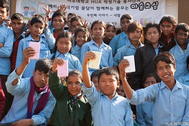 네팔 학생들 약 20명의 단체사진이며 가장 앞 줄에 있는 학생들은 모두 한 손에 포켓포토를 들고 포즈를 취하고 있다.
