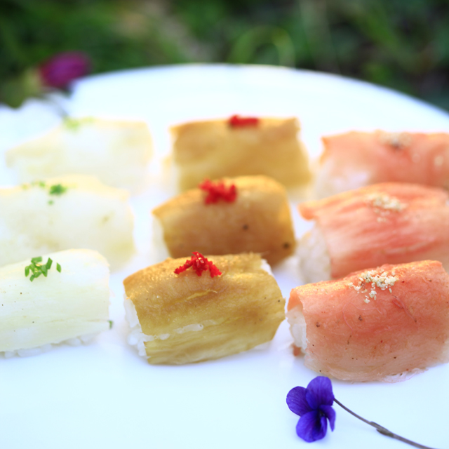 세 가지 다른 재료와 색을 가진 초밥이 흰 접시 위에 올려져 있다.