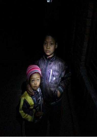 어두운 밤 골목에서 찍은 네팔 남매의 사진. 남매의 얼굴에 손전등을 비춰 찍은 사진이다.