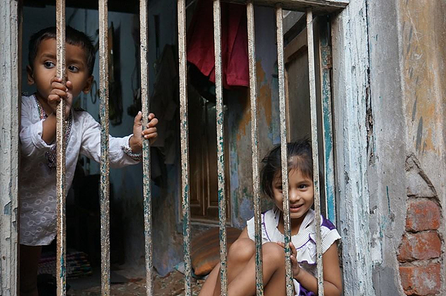 인도 아이 두명이 철조망 안에서 미소를 짓고 있다