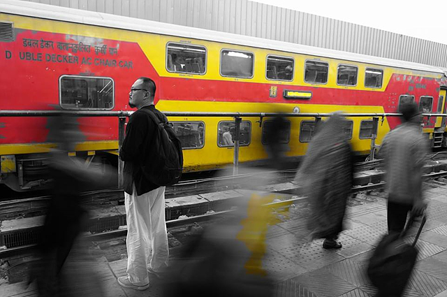 열차를 기다리는 길잡이 아저씨. 빨간색과 노란색의 열차 외에는 흑백으로 보인다. 