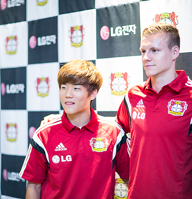 붉은 색 유니폼을 입은 류승우 선수의 모습. 다른 외국인 선수와 어깨동무를 하고 있다. 