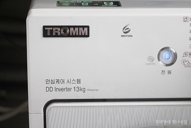 LG전자 트롬 세탁기. 전원버튼과 '안심케어 시스템' 글씨가 보인다.