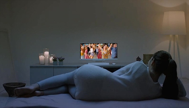 한 여성이 누워서 LG 일체형 PC를 통해 영화를 관람하고 있다.