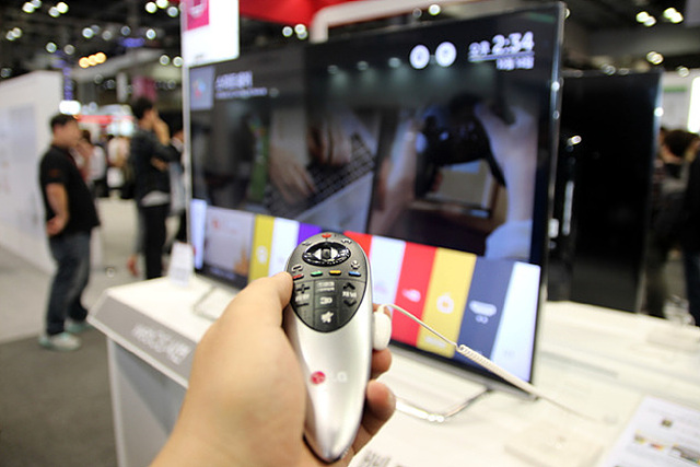 LG 스마트+ TV의 리모콘을 조작하고 있다.