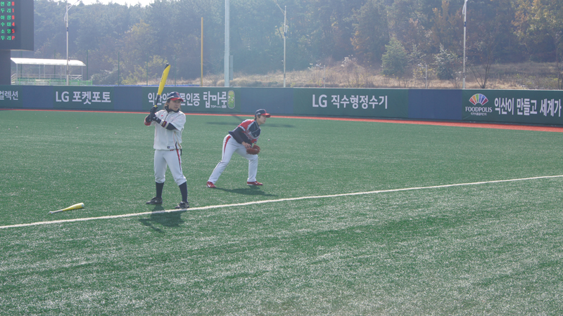 서울 비밀리에와 구리 나인빅스의 경기 시작 전 몸을 푸는 선수들의 모습. 한 선수는 야구배트를 들고 서있고 뒤에 한 선수는 글러브를 낀채 상체를 숙이고 있다.