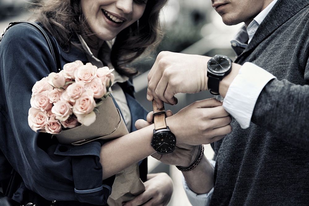 G워치 R을 착용하고 있는 한 남성이 꽃을 들고 있는 여성의 손목에 LG G워치R을 채워주고 있다. 