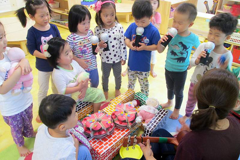 어린이들이 선생님, 친구들과 어울려 함께 노래를 부르고 있다. 