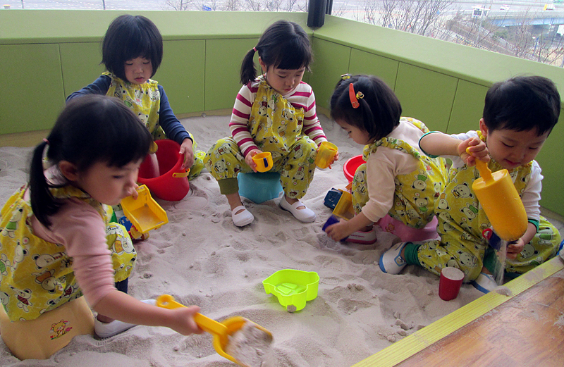 어린이집에서 모래놀이를 하며 놀고 있는 모습