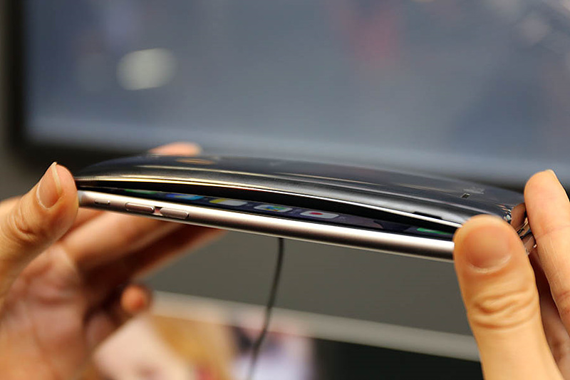 LG G플렉스2의 곡면 디자인을 강조하고 있는 이미지. 일반 스마트폰 위에 G 플렉스2를 겹쳐놓아 스마트폰 사이에 공간이 생긴 모습. 