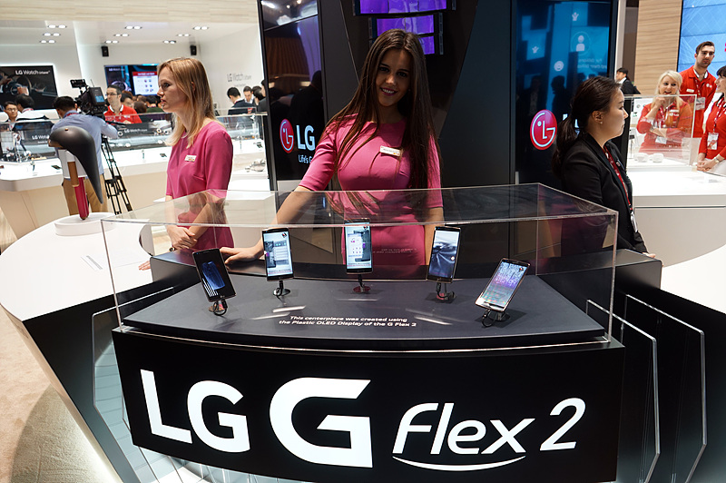 LG G 플렉스2가 전시된 모습 뒤로 한 여자 모델이 웃고 있다. 