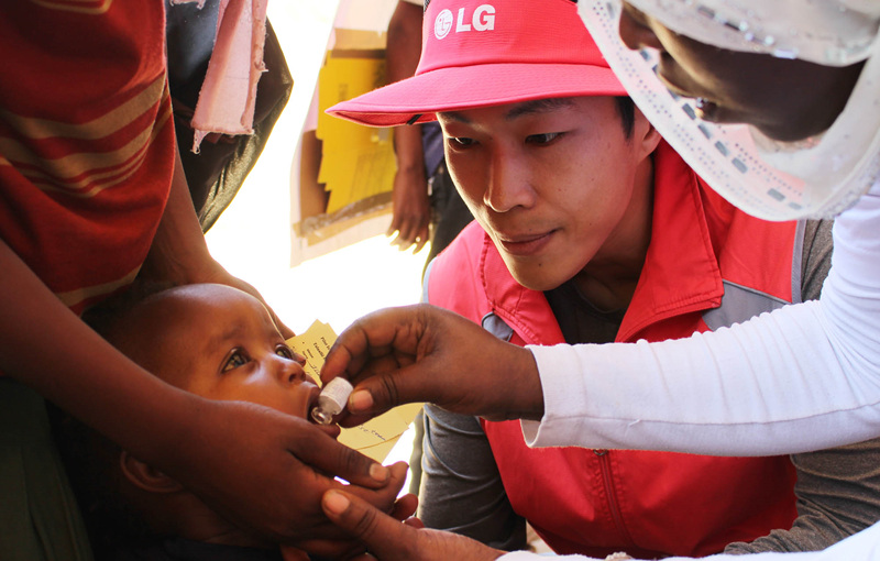 한 에티오피아 어린이에게 약을 먹이고 있는 모습과 그것을 지켜보는 LG전자 직원의 모습 
