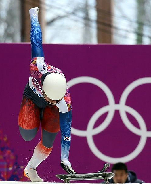 동계올림픽 스켈레톤 대회에서 한 남자 선수가 한 손을 들고 출발을 하고 있다. 