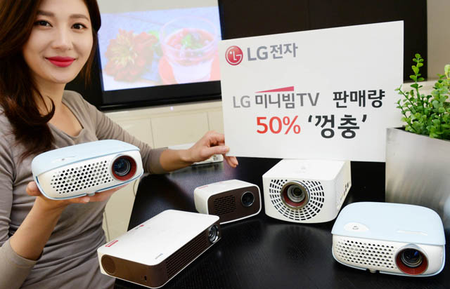 캠핑족과 1인가구를 겨냥한 ‘LG 미니빔 TV’의 국내 월 판매량이 전년 동기 대비 50%이상 증가하며 돌풍을 일으키고 있다. 'LG 미니빔 TV'는 지난 4월에만 약 5,000대가 팔려나가며 인기몰이를 하고 있다. 모델이 제품과 함께 포즈를 취하고 있다.