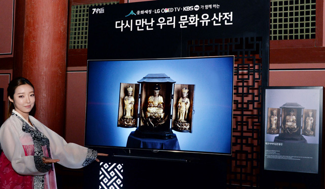 모델이 경복궁 근정전 회랑에서 올레드 TV를 통해 일본 고려박물관에 전시된 목조아미타삼존불감을 소개하고 있습니다.