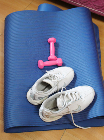 요가매트위에 운동화와 운동기구가 놓여져 있는 모습