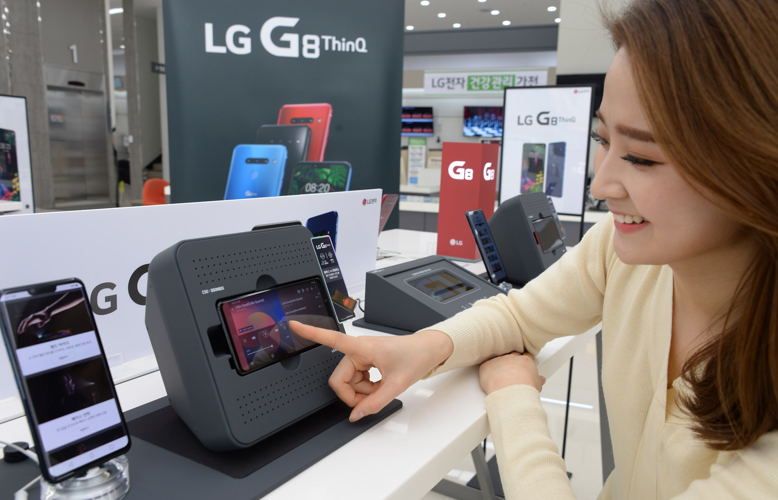 7일, 모델이 LG 베스트샵 서울양평점에서 붐박스부스터에 거치된 LG G8 ThinQ의 스테레오 사운드를 체험해보고 있다. LG G8 ThinQ 후면은 카메라 모듈부 돌출을 아예 없앴고, 전면에는 수화부 리시버의 작은 흔적조차 없앤 매끈한 디자인을 자랑한다.