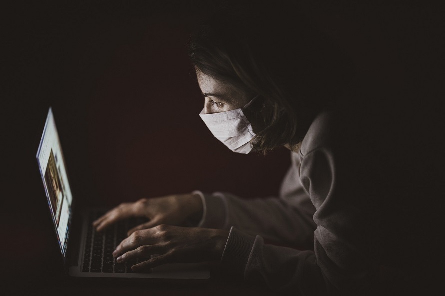 마스크 쓴 여성이 노트북을 들여다보는 모습