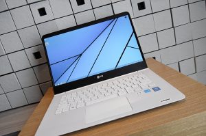 갈색 테이블에 놓인 LG 그램 14. 격자무늬 바탕화면이 보인다.