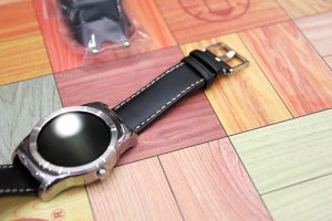 검은색 스트랩의 스마트 워치가 테이블 위에 놓여져 있다.