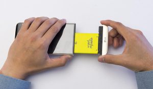 손으로 LG G5 모듈형 배터리를 빼내고 있는 모습