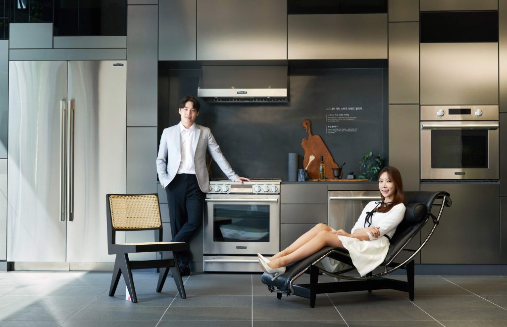 모델이 까시나의 대표 작품 중 하나인 LC4 라운지 체어(LC4 Lounge Chair)에 앉아 가전과 가구가 조화를 이루는 주방 공간을 소개하고 있다.