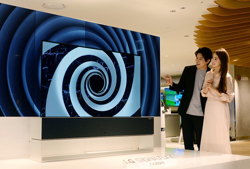 롯데백화점 본점에서 고객들이 화면을 말았다 펼치는 ‘LG 시그니처 올레드 R’을 살펴보고 있다