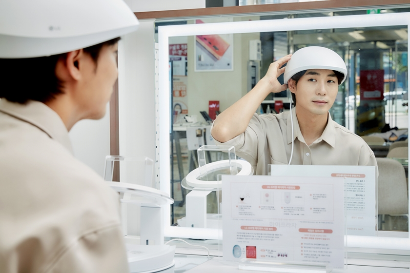 LG전자 모델이 서울 관악구 LG베스트샵 봉천점에 설치돼 있는  LG 프라엘 메디헤어 전용 체험공간에서 메디헤어를 착용해보고 있다.