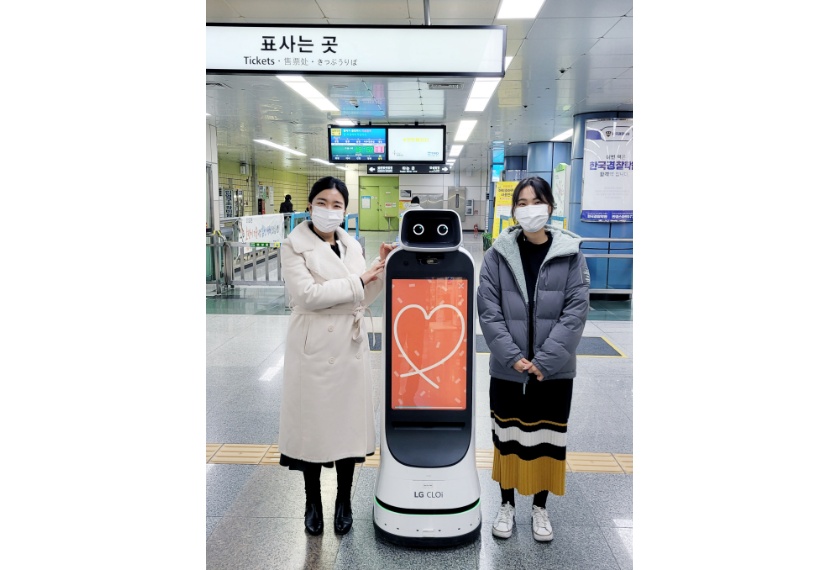 지하철을 이용하는 시민이  LG 클로이 가이드봇의 터치스크린에 원하는 문구를 입력하고 함께 기념사진을 촬영하고 있다. 