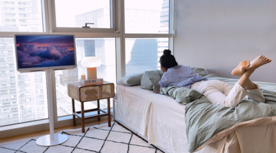 침실 옆에 놓인 LG 스탠바이미와 침대에 누워있는 여성