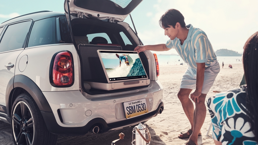 해변가에 주차된 자동차 트렁크에 LG전자의 스탠바이미Go를 조작하는 남성의 모습