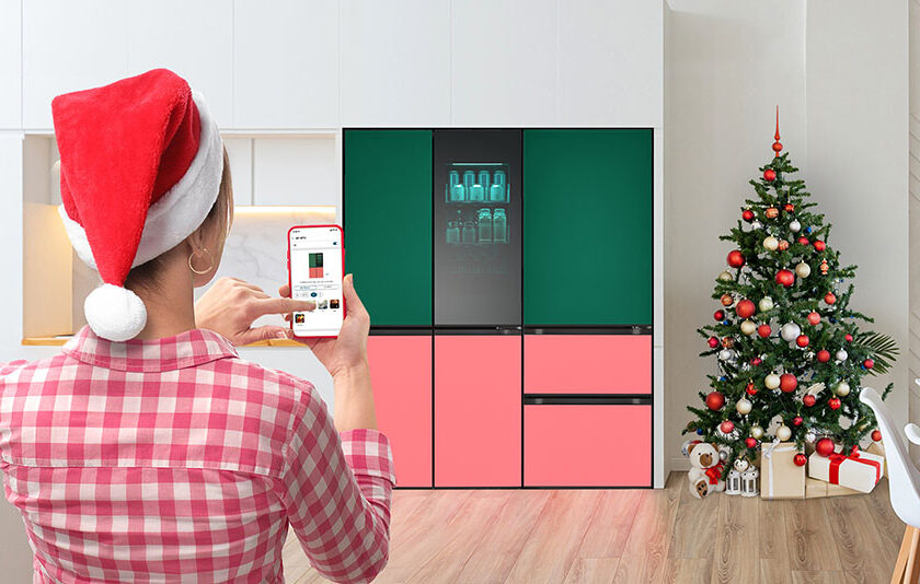 산타 모자를 쓴 여성이 ThinQ앱으로 LG전자 냉장고를 조작하는 모습