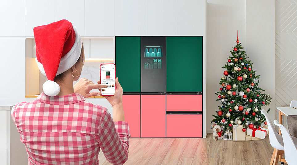 산타 모자를 쓴 여성이 ThinQ앱으로 LG전자 냉장고를 조작하는 모습