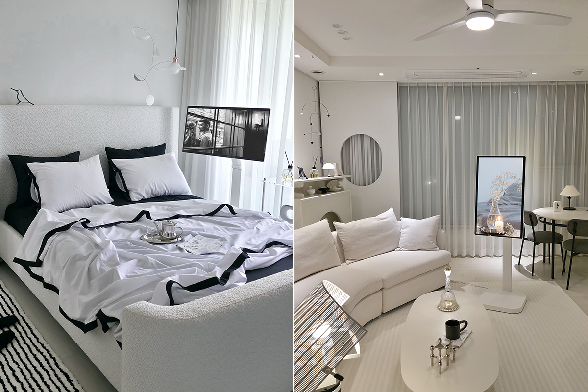 왼쪽은 흑백 베딩과 흰색 벽이 있는 침실로, 침대 옆에 영화가 재생되는 모니터가 있다. 오른쪽은 흰색 소파와 원형 테이블이 있는 거실이며, 앞에는 세로 모니터에 꽃병 사진이 표시되어 있다.