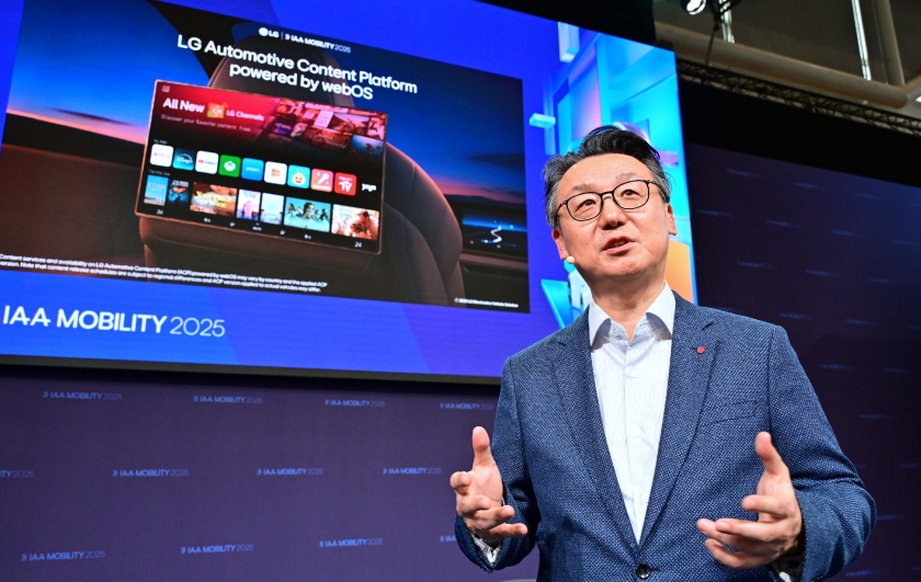 LG전자 은석현 VS 사업본부장이 ‘IAA Mobility 2025’ 행사장에서 LG의 차량용 콘텐츠 플랫폼(webOS 기반)을 소개하고 있다. 무대 뒤 대형 화면에는 자동차 뒷좌석에 설치된 디스플레이 화면이 보이며, 넷플릭스, 유튜브, 디즈니플러스 등 다양한 콘텐츠 앱 아이콘이 표시되어 있다. 연사는 정장을 입고 프레젠테이션을 진행하며 손짓으로 설명하고 있다.