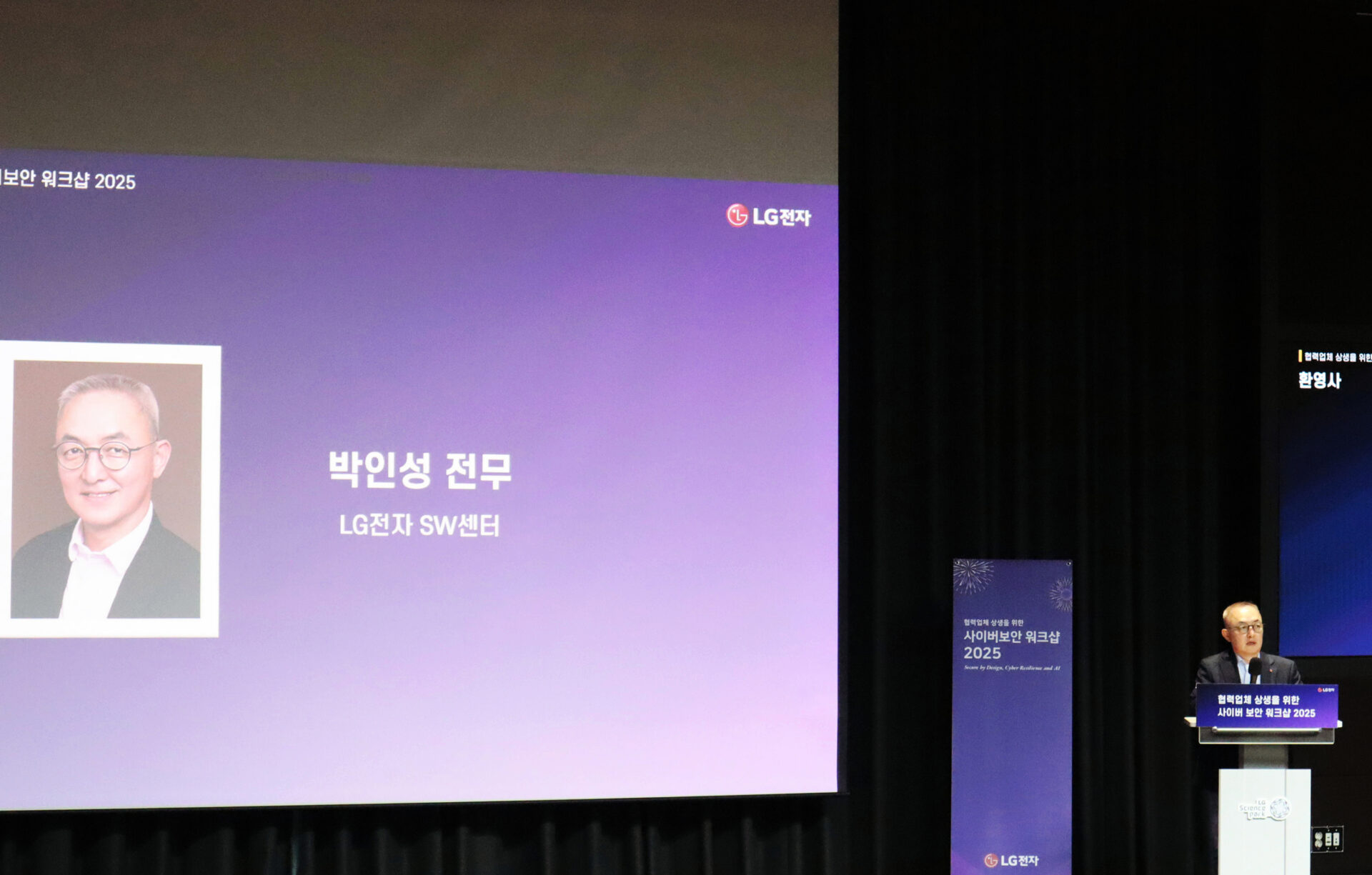 무대 위 스크린에 ‘박인성 전무 LG전자 SW센터’라는 이름과 인물 사진이 표시되어 있다. 오른쪽에는 박인성 전무가 연단에 서서 발표를 진행하고 있다. 스크린과 연단에는 ‘협력업체 상생을 위한 사이버 보안 워크샵 2025’라는 문구와 LG전자 로고가 보인다.