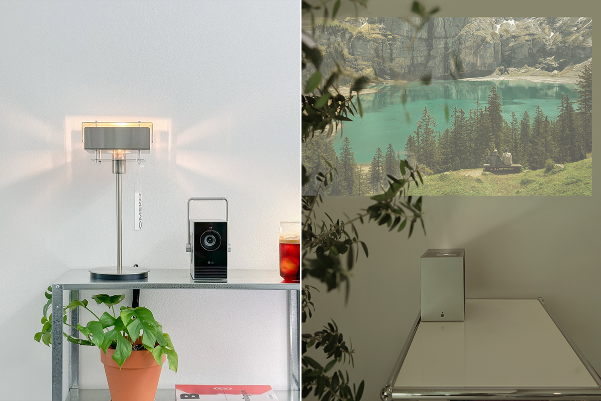 메탈 선반 위에 스탠드 조명과 화분, 음료와 함께 시네빔 큐브가 놓여 있으며, 조명 아래로 은은한 빛이 벽에 퍼져 있다. 오른쪽 장면에서는 낮은 테이블 위에 시네빔 쇼츠가 배치되어 있고, 장치가 벽에 푸른 호수와 숲 풍경을 크게 투사하고 있다. 이미지 안에는 제품 태그의 “OMEKO” 텍스트가 보이며, 실내 식물의 잎이 일부 화면을 가리며 자연스러운 분위기를 더한다.